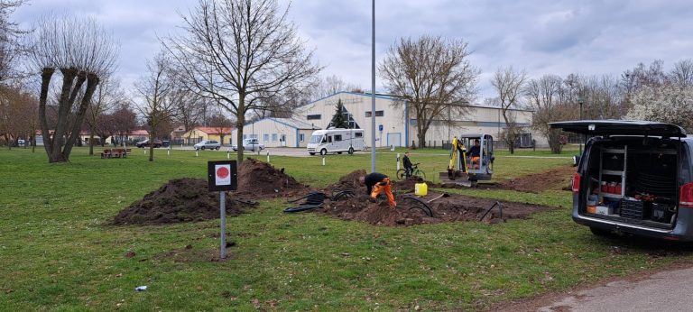 Erdarbeiten mit kleinem Bagger und Werkzeugauto auf einer kahlen Wiese als Vorbereitung für den Bau eines ersten Drohnen-Landeplatzes in Wusterhausen an der Dosse. 